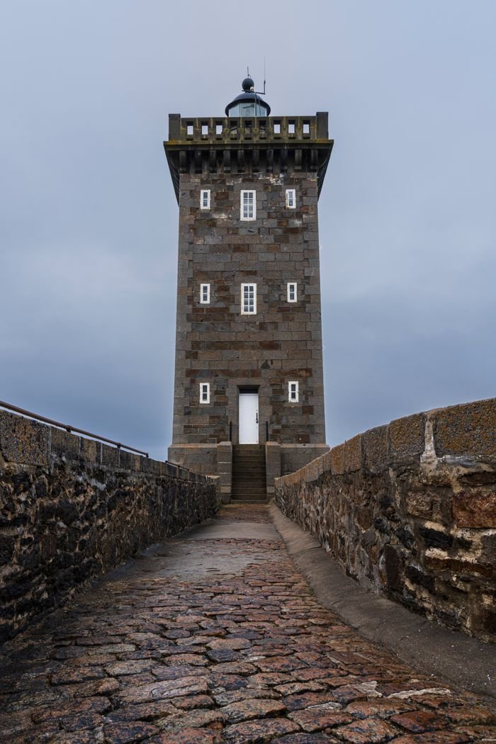 Charming lighthouse in Le Conquet, France, set against a moody sky.