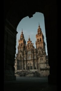 Dramatic view of Santiago de Compostela Cathedral framed by an arch at twilight.